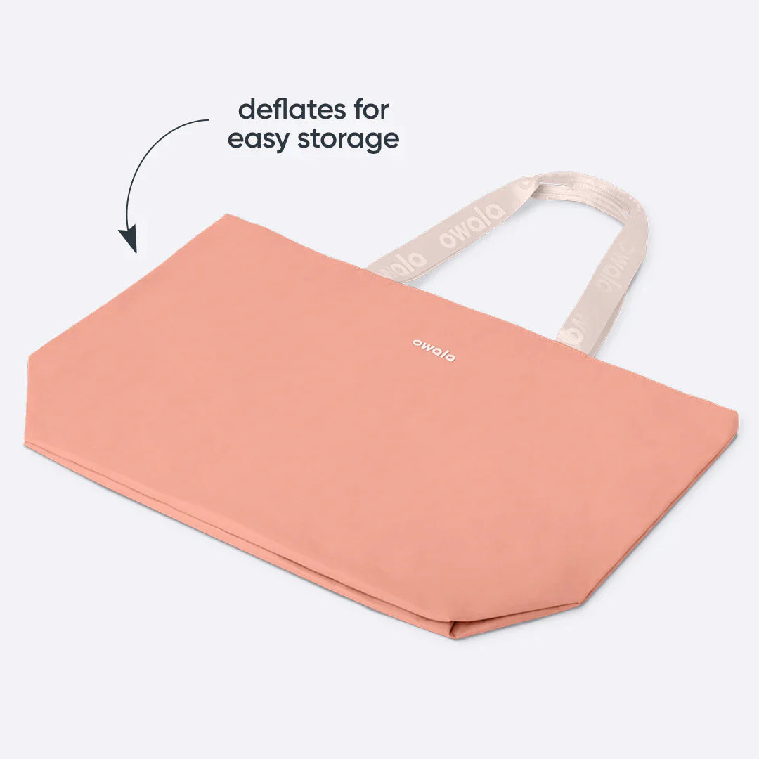 Owala Cloud Insulated Tote in Rosewood shown deflated and folded flat, peach pink body with cream owala-tape handles featuring repeating Owala logo and cream Owala logo on the body, with text overlay reading "deflates for easy storage"